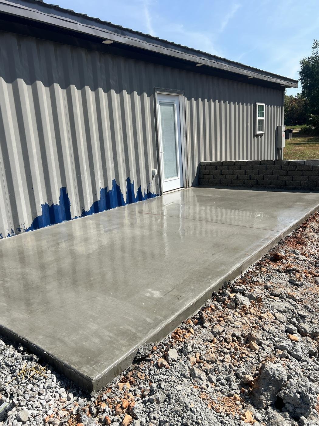 Freshly poured concrete slab beside a metal building