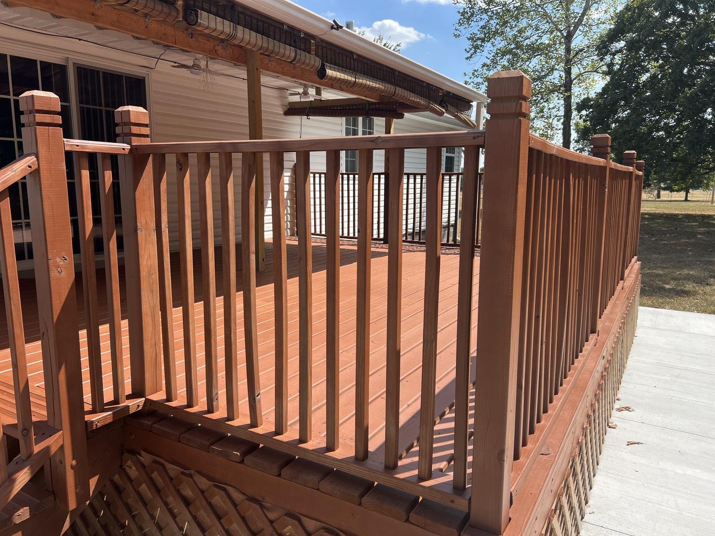 Finished wood deck with a rich red-brown stain and matching spindle railing